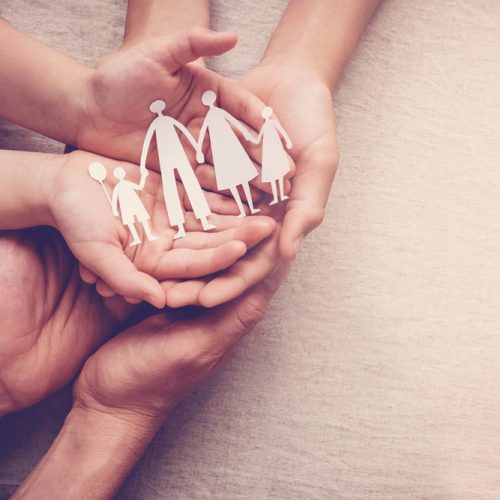 hands holding paper family cutout, family