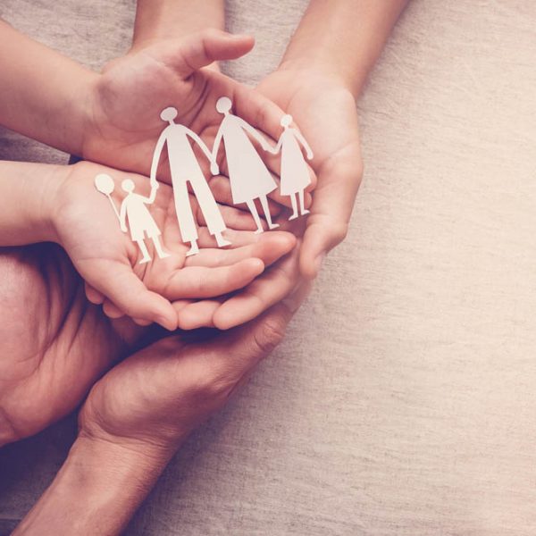 hands holding paper family cutout, family