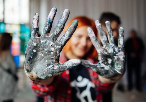 Young person showing hands covered with paint