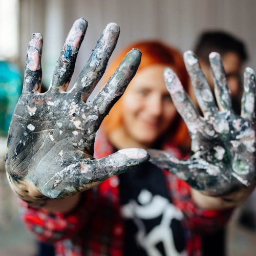 Young person showing hands covered with paint